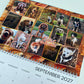 A spiral-bound 2027 calendar page featuring a collage of dog photos with autumn leaves and the text 'hello autumn' in the center. The bottom of the page shows the September 2027 date grid.
