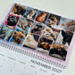 A spiral-bound desk calendar page showing a grid of pet photos with the text 'November 2027' visible at the bottom, photographed on a light neutral background.