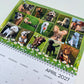 A spiral-bound monthly calendar page for April 2027, featuring a grid of 16 dog photos.