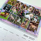 A spiral-bound May 2027 desk calendar page featuring a collage of dog photographs with purple floral accents, photographed on a light background.