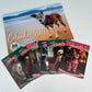 A 2027 spiral bound Many Tears Animal Rescue calendar displayed with several printed holiday cards fanned out in front on a white background. The calendar cover shows a dog on a beach.
